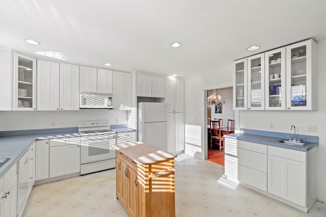 kitchen with sink, white appliances, white cabinetry, and an inviting chandelier