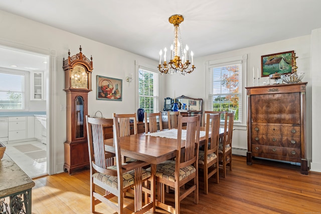 dining space with light wood-type flooring, a baseboard radiator, and a chandelier