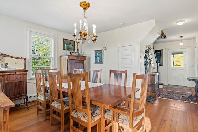 dining area with an inviting chandelier, hardwood / wood-style flooring, and a baseboard radiator