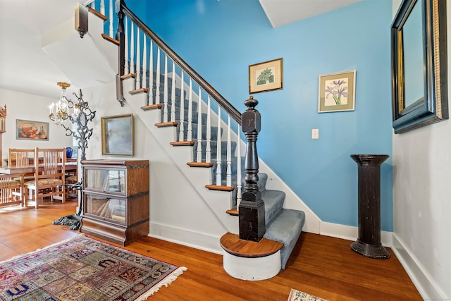 stairway featuring hardwood / wood-style floors and a chandelier