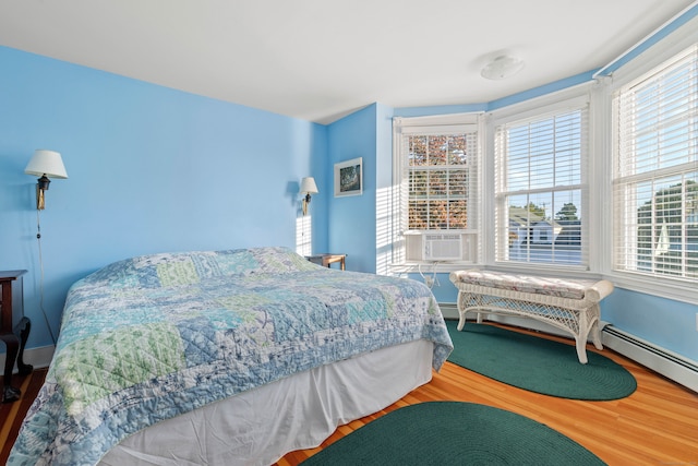 bedroom with cooling unit, a baseboard radiator, and hardwood / wood-style floors