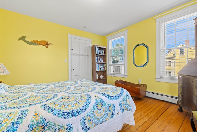 bedroom featuring wood-type flooring, cooling unit, and a baseboard radiator