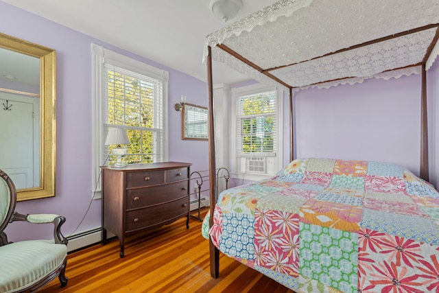 bedroom featuring multiple windows, wood-type flooring, and baseboard heating