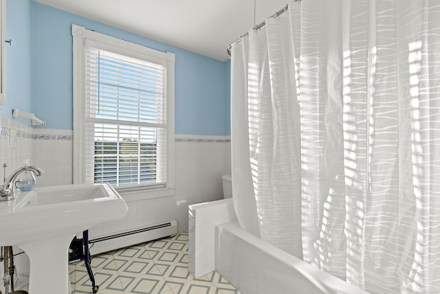 bathroom featuring a baseboard radiator, toilet, shower / tub combo with curtain, and tile walls