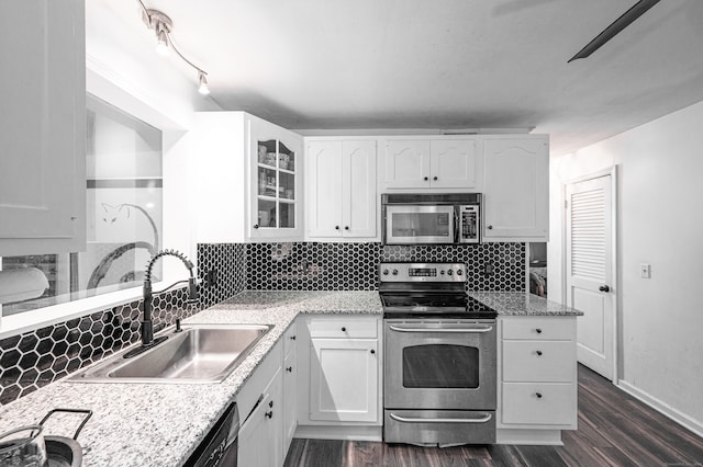 kitchen with appliances with stainless steel finishes, sink, backsplash, dark hardwood / wood-style flooring, and white cabinets