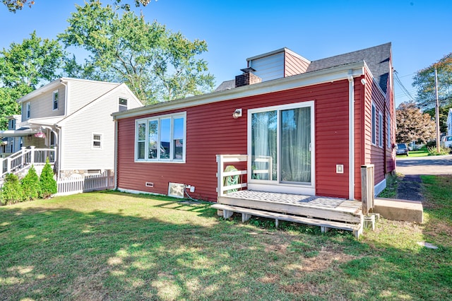 rear view of property featuring a deck and a lawn