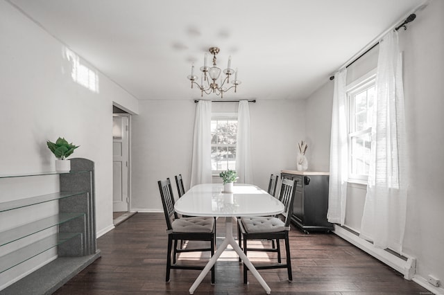 dining area with dark wood-type flooring, a notable chandelier, a baseboard heating unit, and plenty of natural light