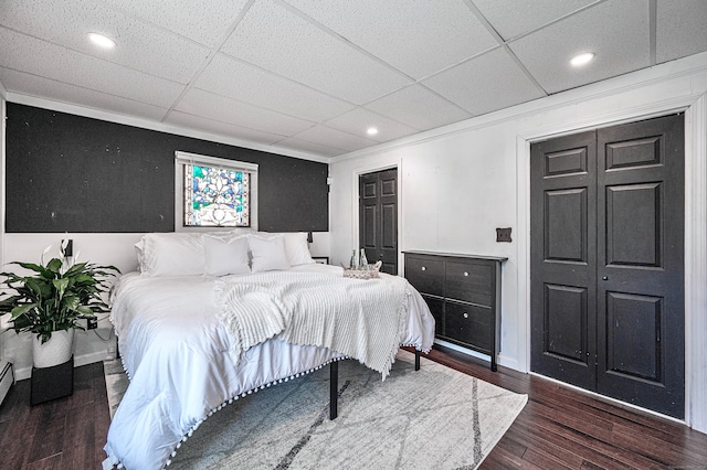 bedroom with a drop ceiling, a closet, and dark wood-type flooring