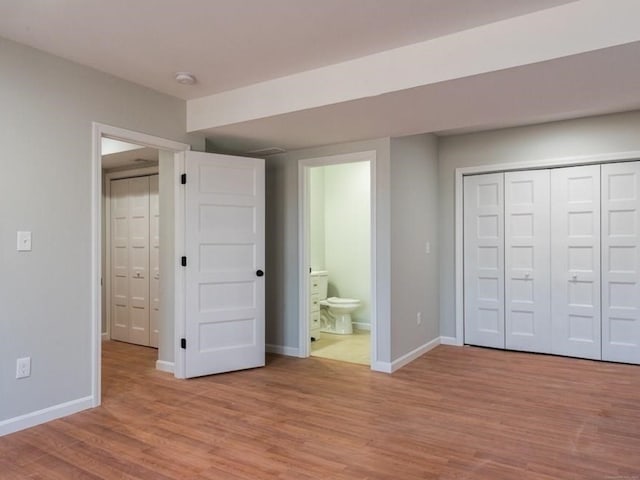 unfurnished bedroom featuring a closet, connected bathroom, and light hardwood / wood-style floors