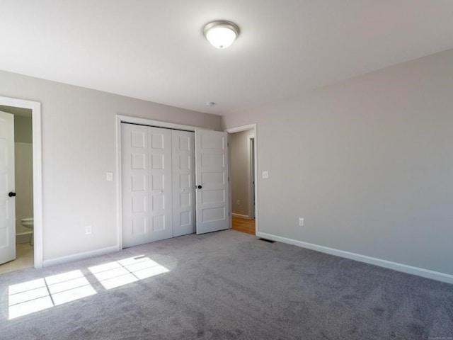 unfurnished bedroom with a closet, connected bathroom, and light carpet