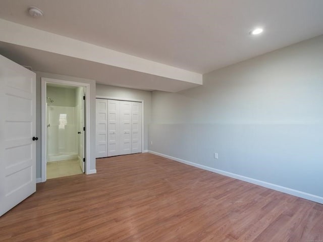 unfurnished bedroom featuring hardwood / wood-style flooring, ensuite bath, and a closet