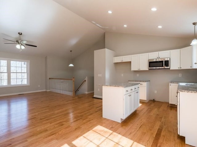 kitchen featuring white cabinets, decorative light fixtures, light hardwood / wood-style flooring, and vaulted ceiling