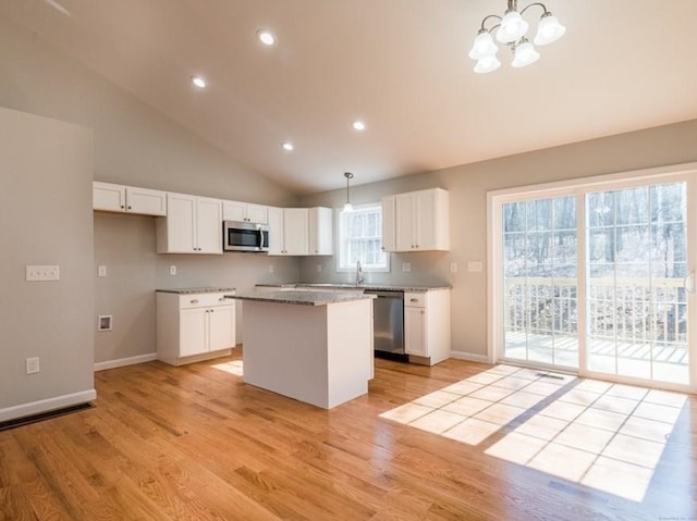 kitchen featuring light wood-type flooring, pendant lighting, a kitchen island, stainless steel appliances, and white cabinets