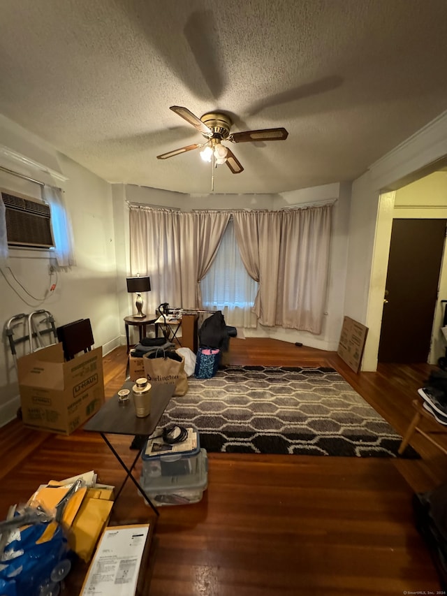 interior space with a wall unit AC, ceiling fan, dark wood-type flooring, and a textured ceiling