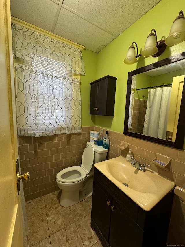 bathroom featuring vanity, tile walls, and toilet