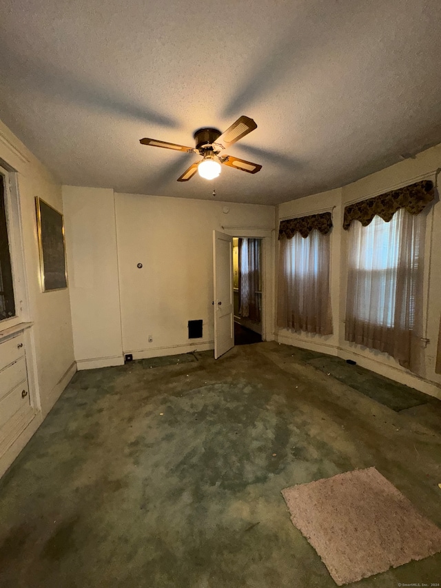 carpeted spare room with ceiling fan and a textured ceiling