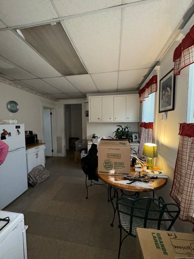 kitchen with a paneled ceiling, white fridge, and white cabinetry