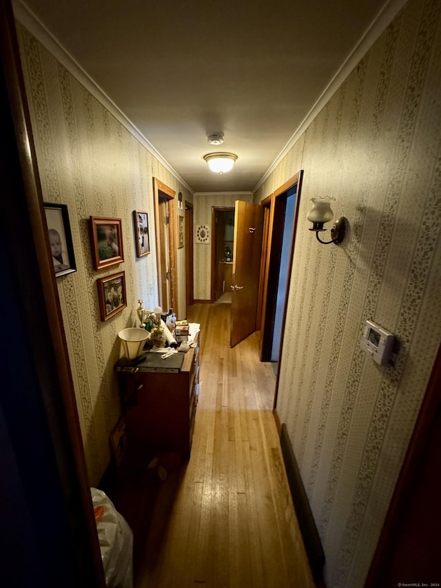 hall with wallpapered walls, light wood-type flooring, and ornamental molding