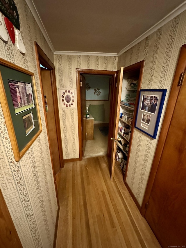 hall with wallpapered walls, wood finished floors, and ornamental molding