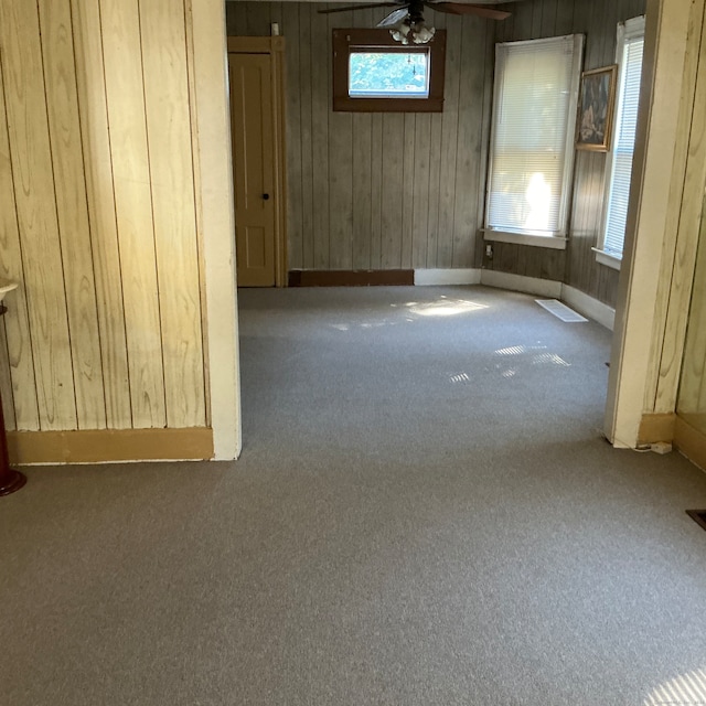 carpeted empty room featuring ceiling fan and wooden walls