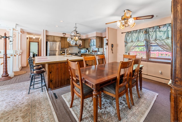 dining room featuring dark colored carpet, sink, ceiling fan, and a baseboard heating unit