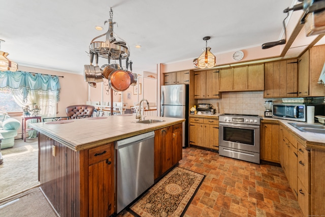 kitchen featuring an island with sink, decorative light fixtures, sink, and stainless steel appliances