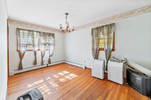 empty room with an inviting chandelier, baseboard heating, and light hardwood / wood-style floors