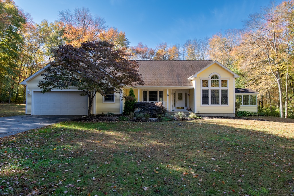 ranch-style house with covered porch, a garage, and a front lawn