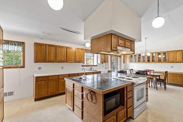 kitchen with white range with electric stovetop, a sink, brown cabinetry, black microwave, and a kitchen island with sink