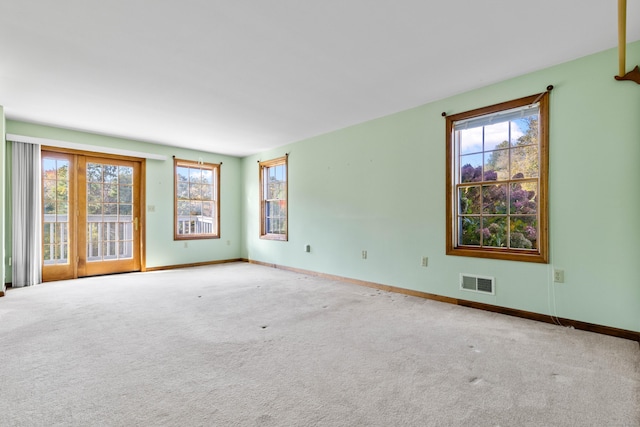 unfurnished room featuring plenty of natural light, baseboards, visible vents, and carpet