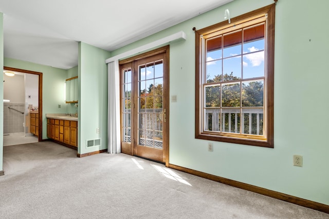 doorway featuring baseboards, visible vents, and light colored carpet