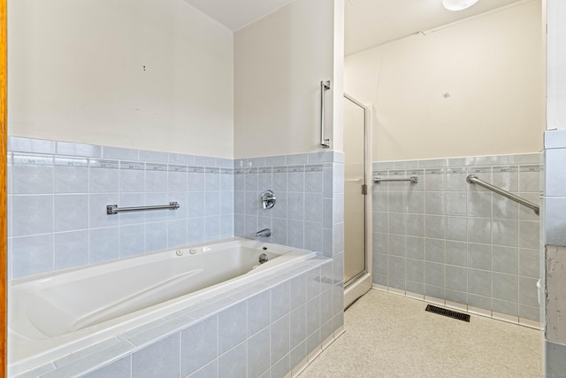 full bath with a shower stall, a garden tub, wainscoting, tile walls, and visible vents