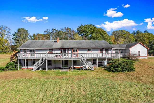 rear view of property featuring stairway, a lawn, a chimney, and a deck