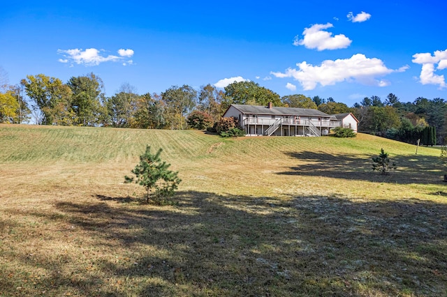 view of yard featuring a wooden deck, a rural view, and stairs