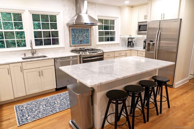 144 Hawks Hill Rd, New Canaan, CT 06840 - kitchen featuring stainless steel appliances, wall chimney exhaust hood, tasteful backsplash, a breakfast bar area, and light wood-style floors