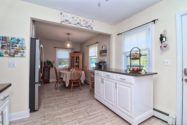 kitchen with stainless steel fridge, dark stone countertops, pendant lighting, white cabinetry, and baseboard heating