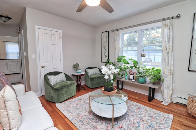 living room featuring light wood-type flooring, ceiling fan, and baseboard heating