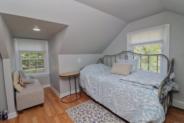 bedroom with multiple windows, vaulted ceiling, and light hardwood / wood-style flooring