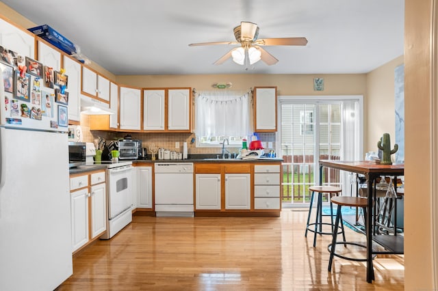 kitchen with white appliances, white cabinets, tasteful backsplash, sink, and ceiling fan