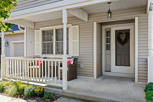 view of exterior entry featuring a garage and a porch