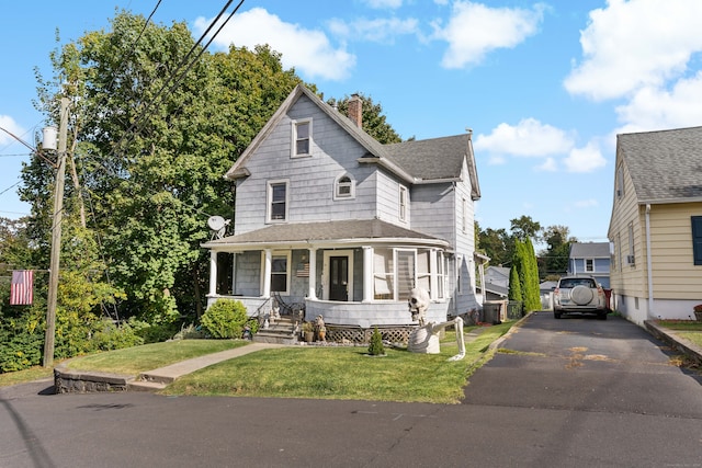 view of front of house featuring a front yard, a porch, and central AC unit