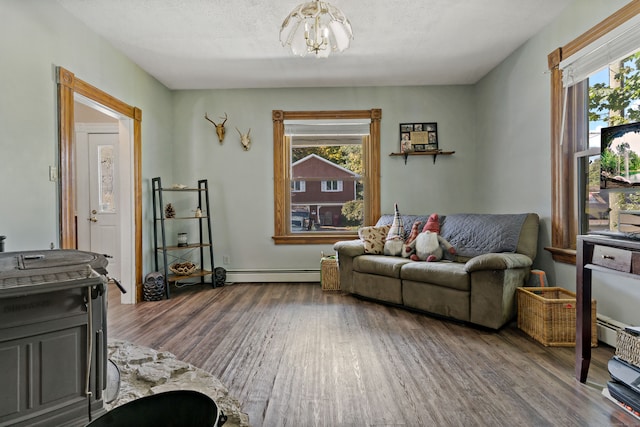 living room featuring wood-type flooring, an inviting chandelier, a textured ceiling, and a baseboard radiator