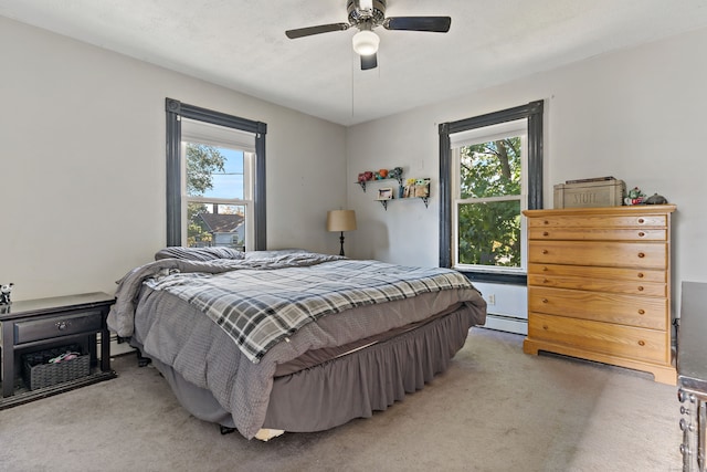 bedroom with multiple windows, ceiling fan, carpet floors, and baseboard heating