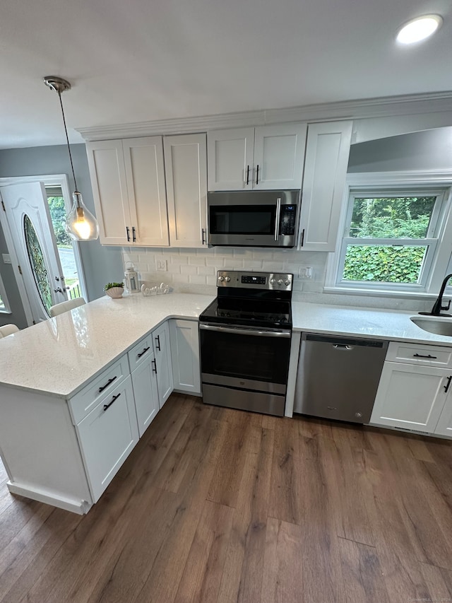 kitchen with sink, decorative light fixtures, white cabinetry, appliances with stainless steel finishes, and dark hardwood / wood-style floors