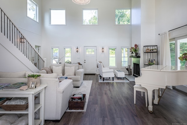 living room featuring dark wood-type flooring, a high ceiling, and a healthy amount of sunlight