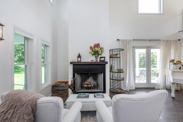 living room featuring french doors, wood finished floors, a fireplace, and a towering ceiling