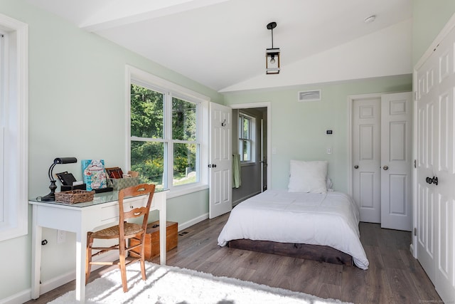 bedroom with wood finished floors, visible vents, baseboards, and vaulted ceiling