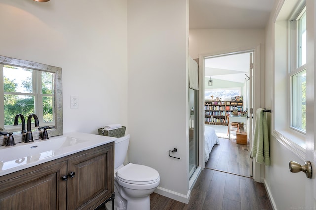 bathroom with a shower stall, vanity, toilet, wood finished floors, and baseboards