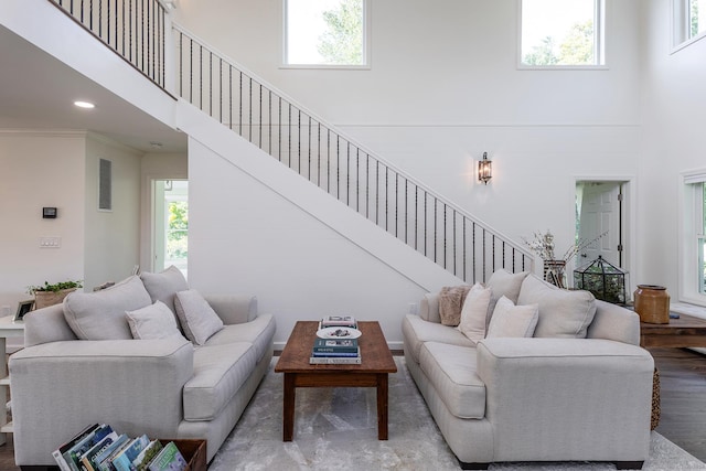 living area featuring a towering ceiling, recessed lighting, crown molding, stairs, and wood finished floors