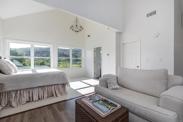 bedroom featuring visible vents, high vaulted ceiling, wood finished floors, and multiple windows